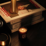 Coffee table with a stack of books, 70s style lamp & lit candle in an amber glass container.
