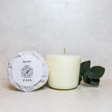 Two wax candles in recycled packaging with a eucalyptus branch