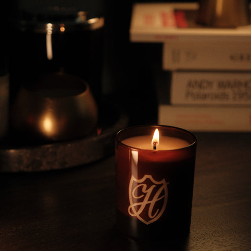 Lit candle in a moody living room with coffee table books in the background