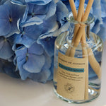 Glass diffuser with fragrance and a blue hydrangea besides