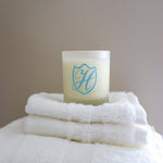 Glass wax candle holder on a stack of white fluffy towels