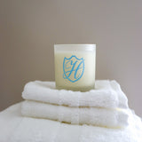 Glass wax candle holder on a stack of white fluffy towels