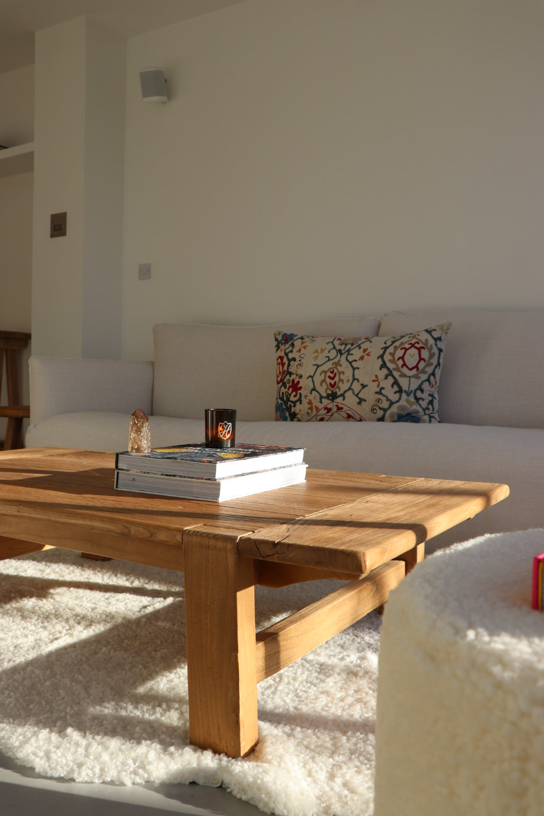 Wooden coffee table with cream boucle rug in a minimalistic living room setting