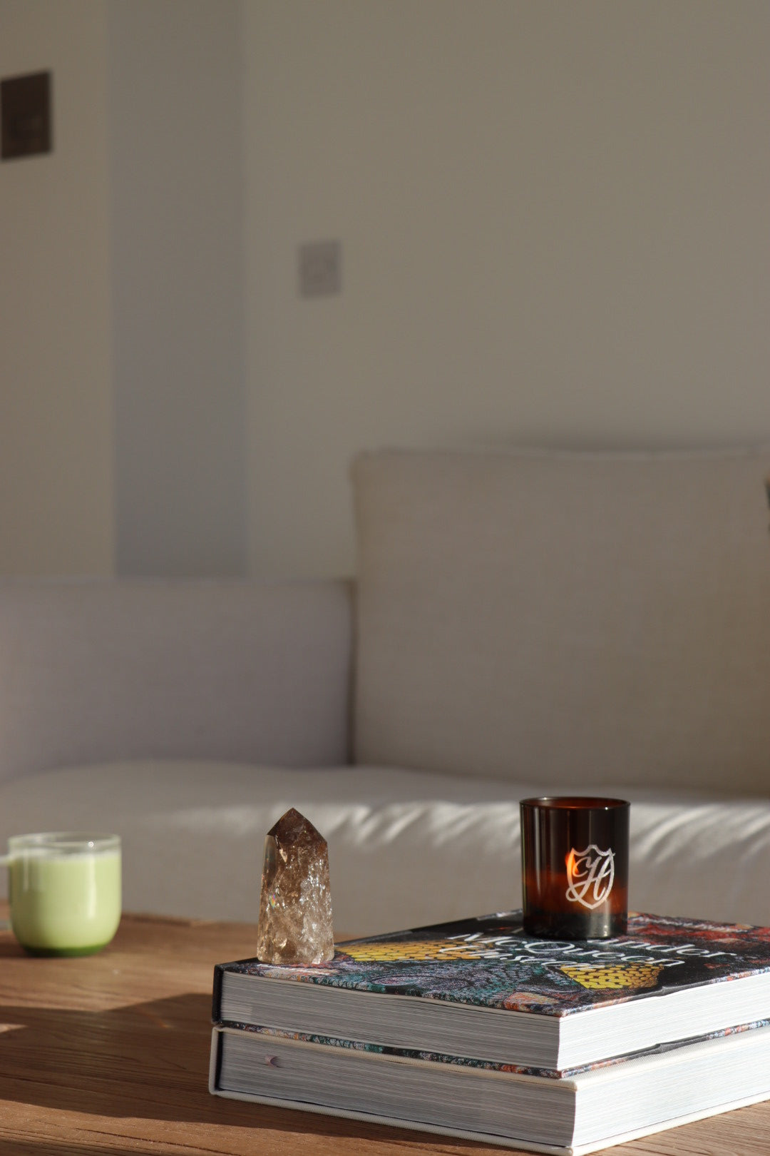 Wooden coffee table with a matcha latte, coffee table books, candle & crystal placed carefully