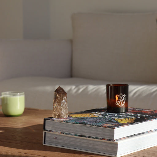 Close up of a coffee table with books, crystal, latte and glass candle holder