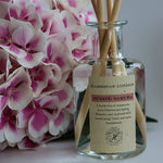 glass diffuser with a pink hydrangea head laying next to it